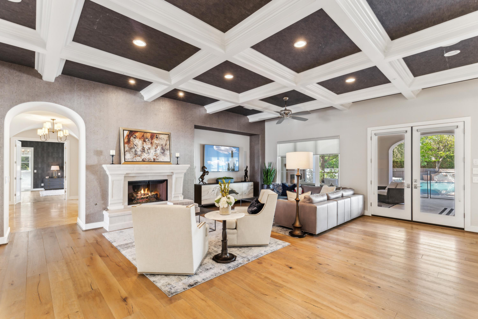 The seating area is arranged around a stone fireplace set into a textured accent wall, with a television positioned nearby and a mix of sofas and lounge chairs.
