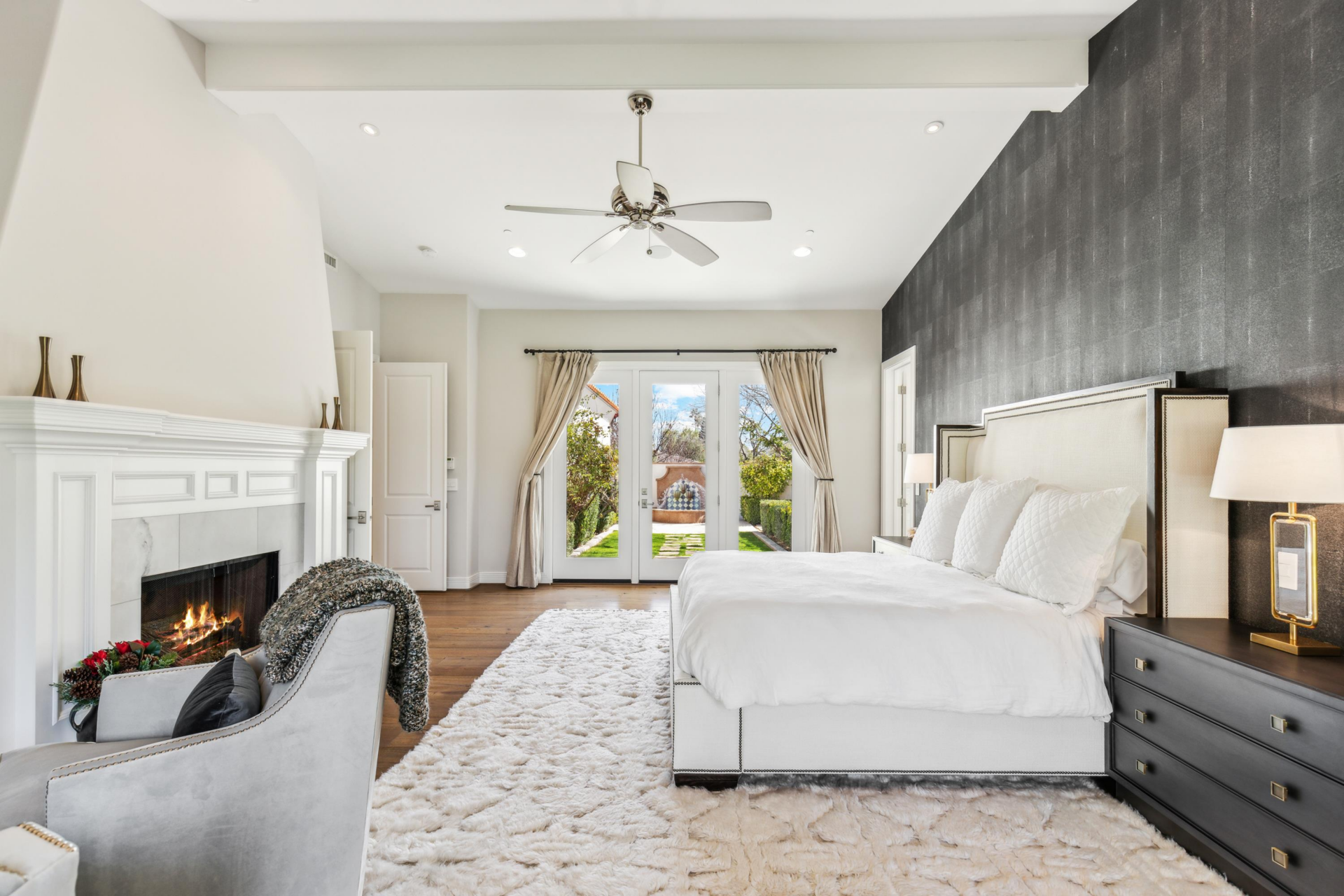 Across from the bed, a separate seating area sits near a white mantel fireplace.