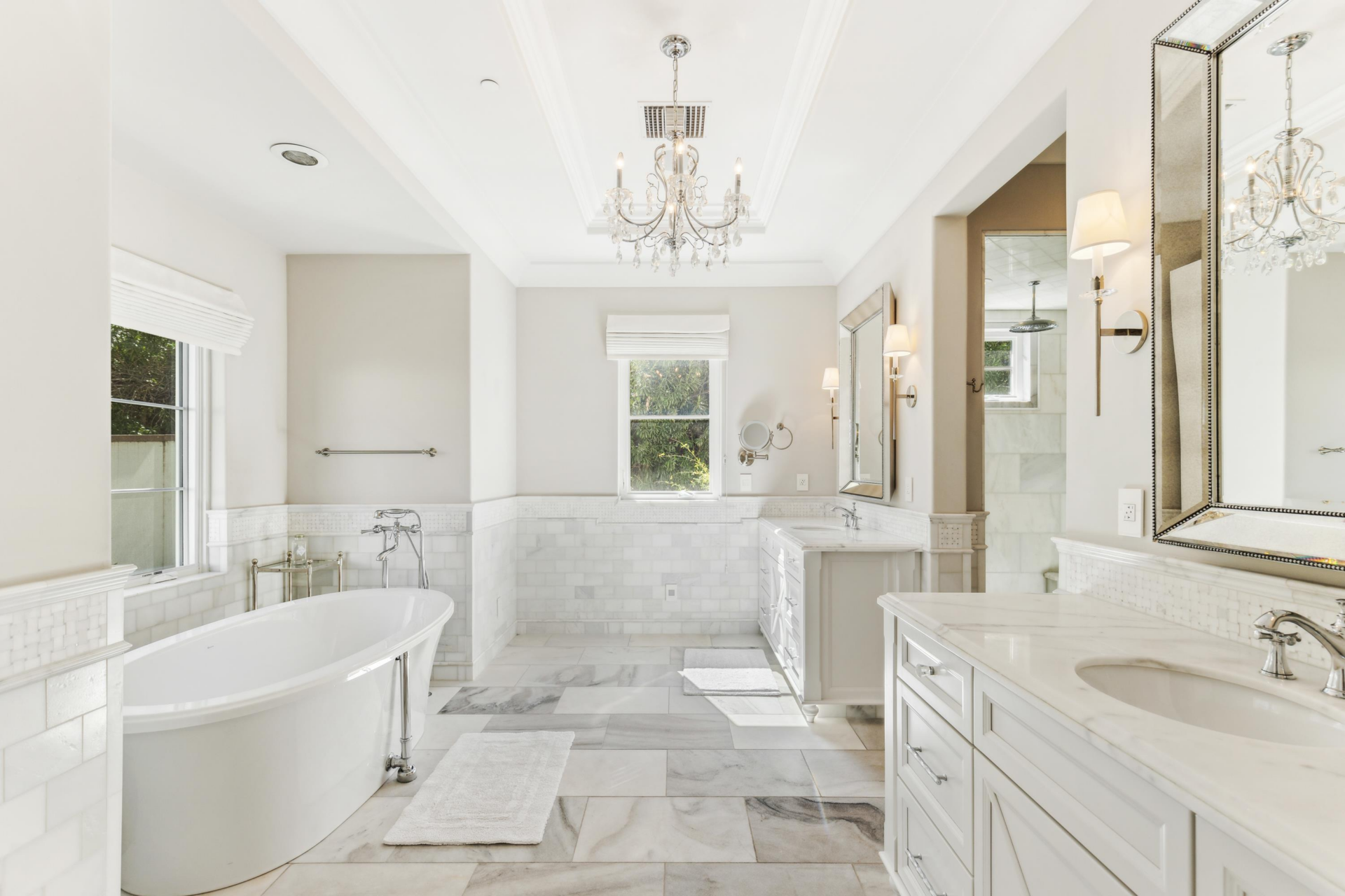 The bathroom has a much lighter palette with marble and white stone used across the flooring, lower walls, and counters. 