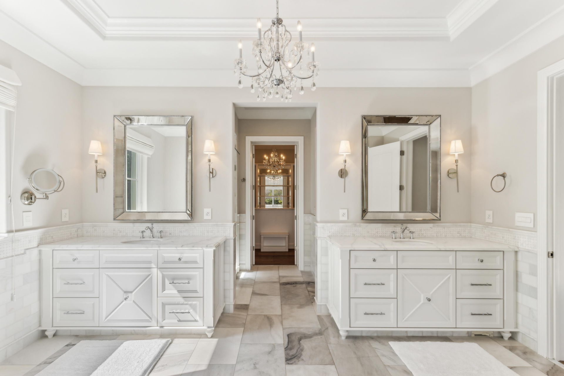 Around the corner, the bathroom extends into a narrow hallway with a water closet and a glass-enclosed shower with a waterfall fixture. 