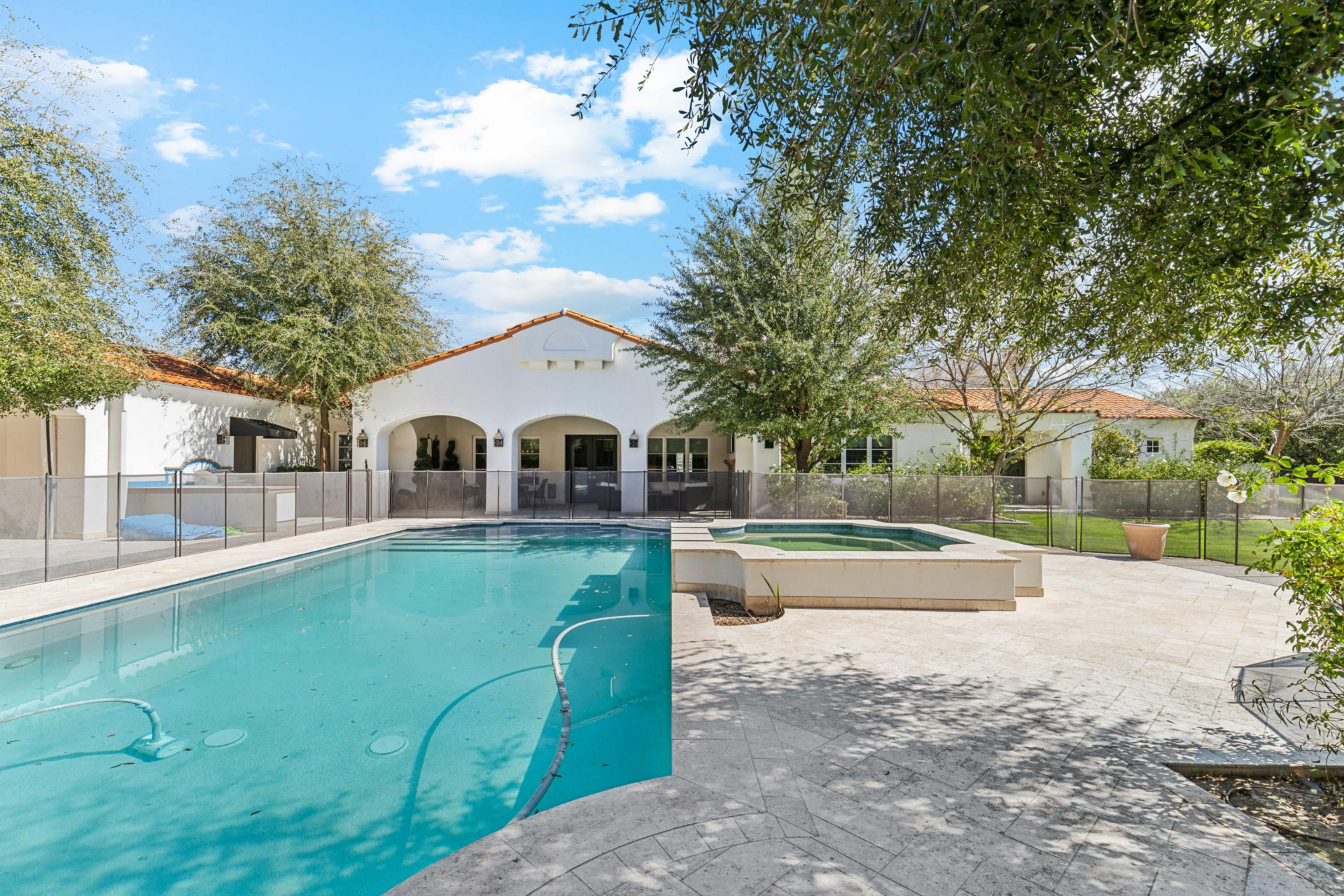 From the patio, the space opens to a gated swimming pool and raised spa surrounded by broad stone decking. 