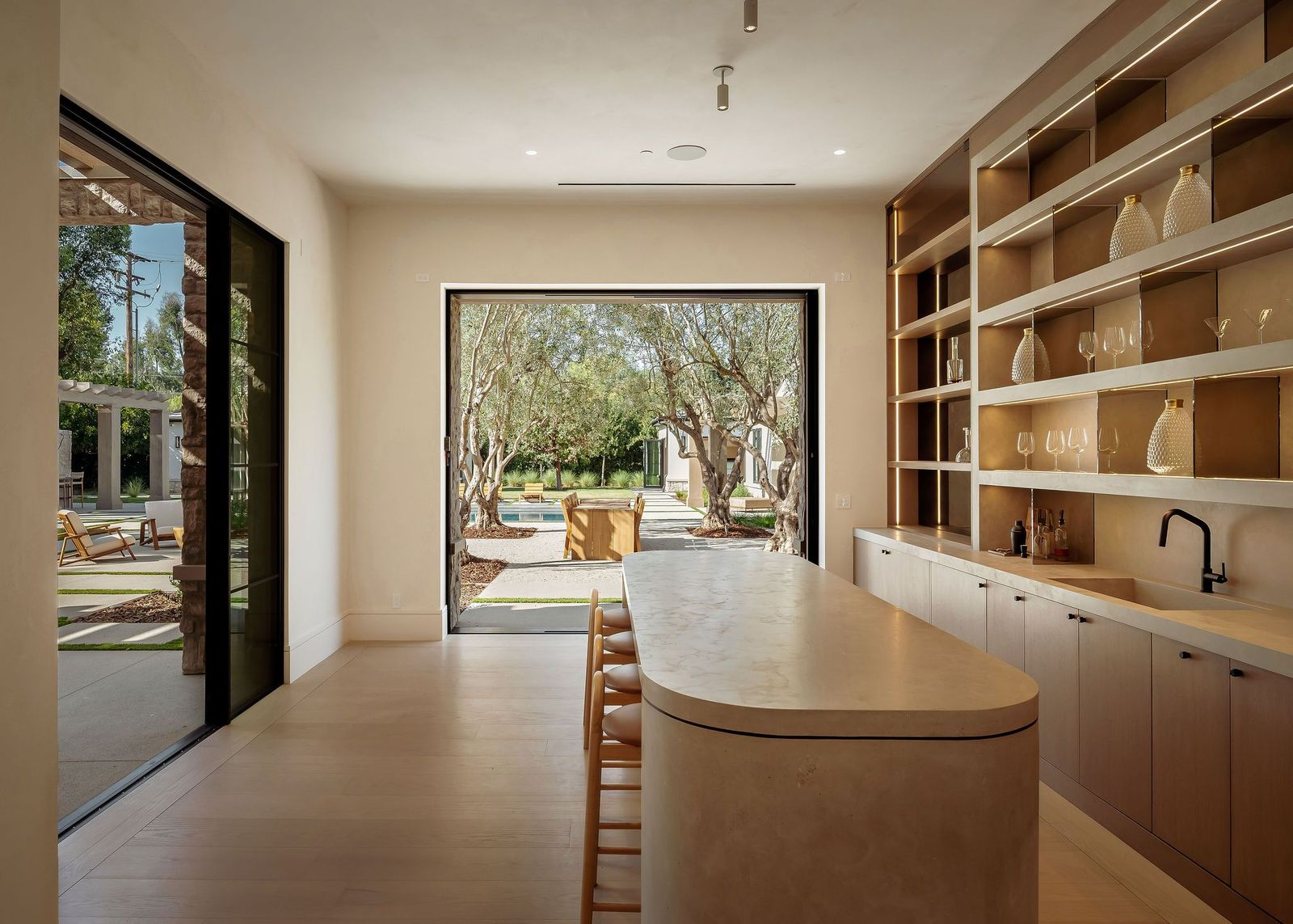 Multiple sets of pocket doors open the room to the surrounding courtyards and outdoor living areas, allowing the bar to function as an indoor-outdoor entertaining space.