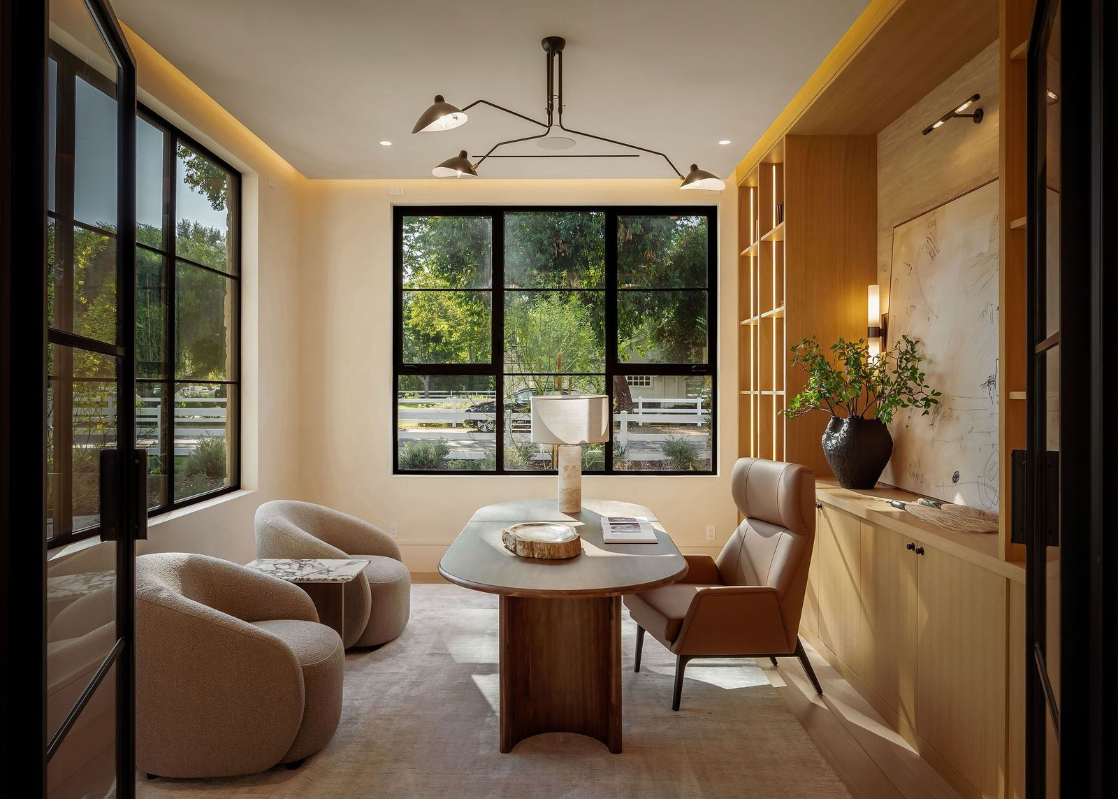 Custom wood cabinetry and open shelving sit behind a desk in the center of the office.
