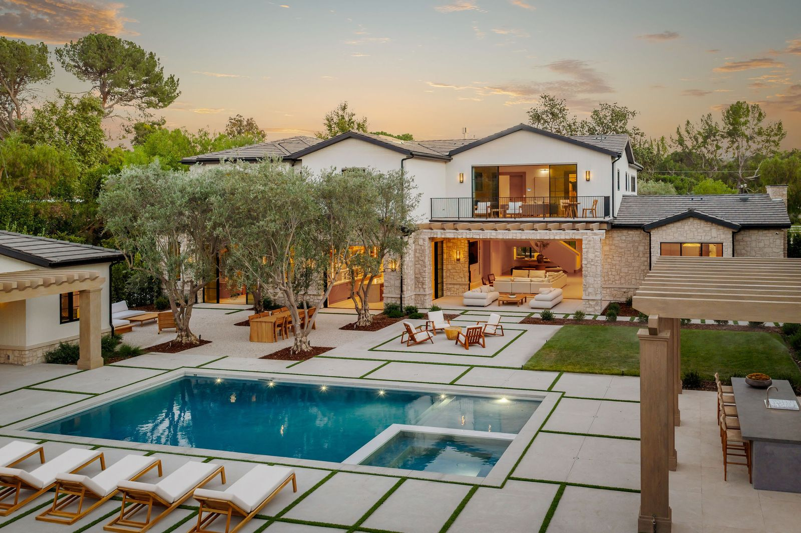 At the center of the backyard is the rectangular swimming pool with an integrated spa, surrounded by paved terraces broken up with narrow bands of grass. 