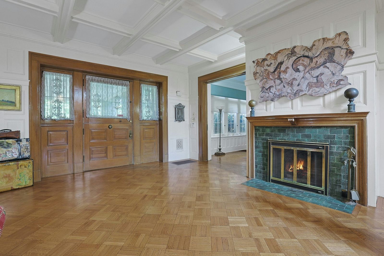The entrance opens into a large central hall finished with parquet wood floors, paneled walls, and a coffered ceiling. 