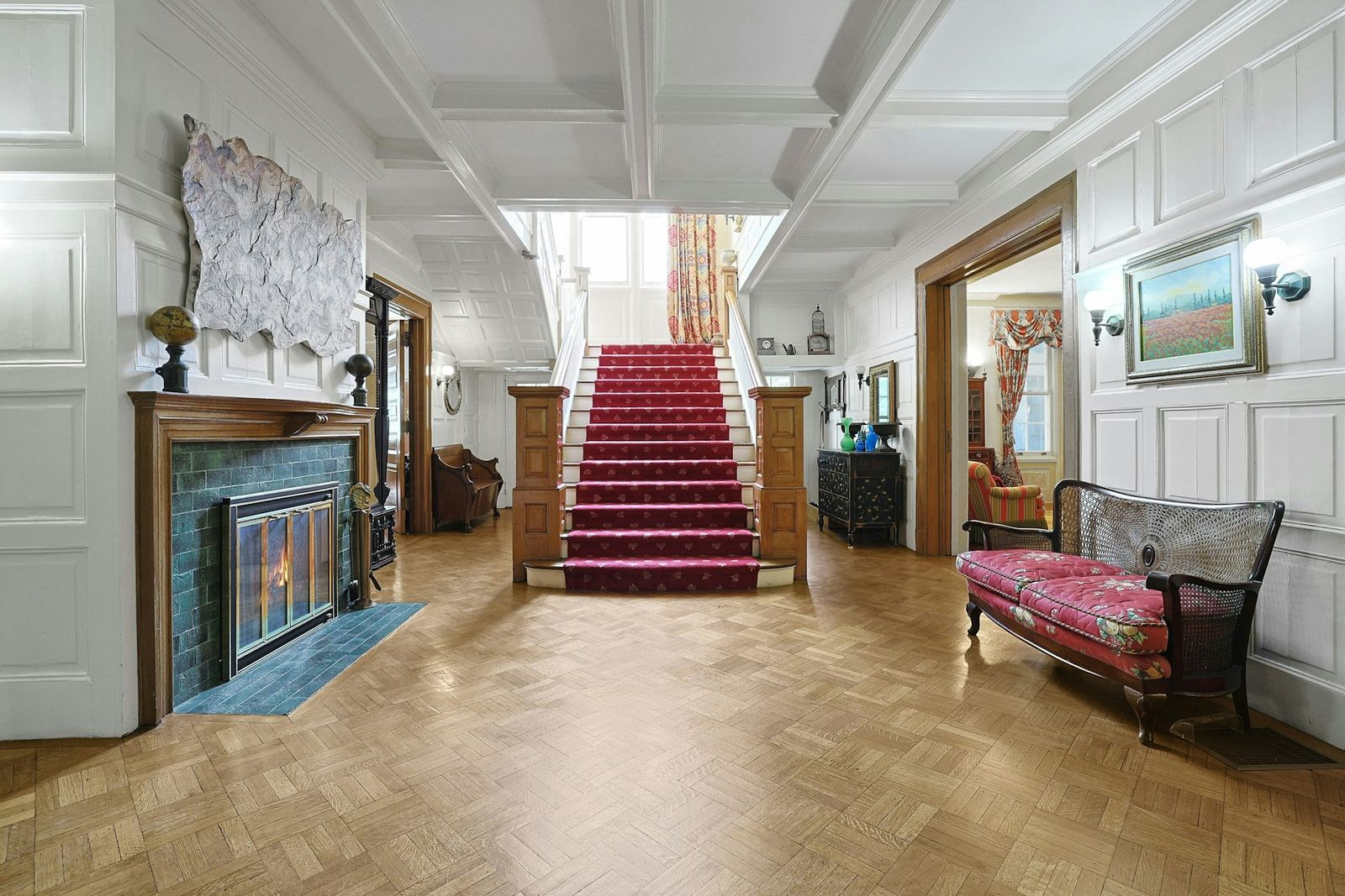 Straight ahead, a wide staircase rises through the middle of the house, creating a central point between the main living spaces that open from either side of the hall.
