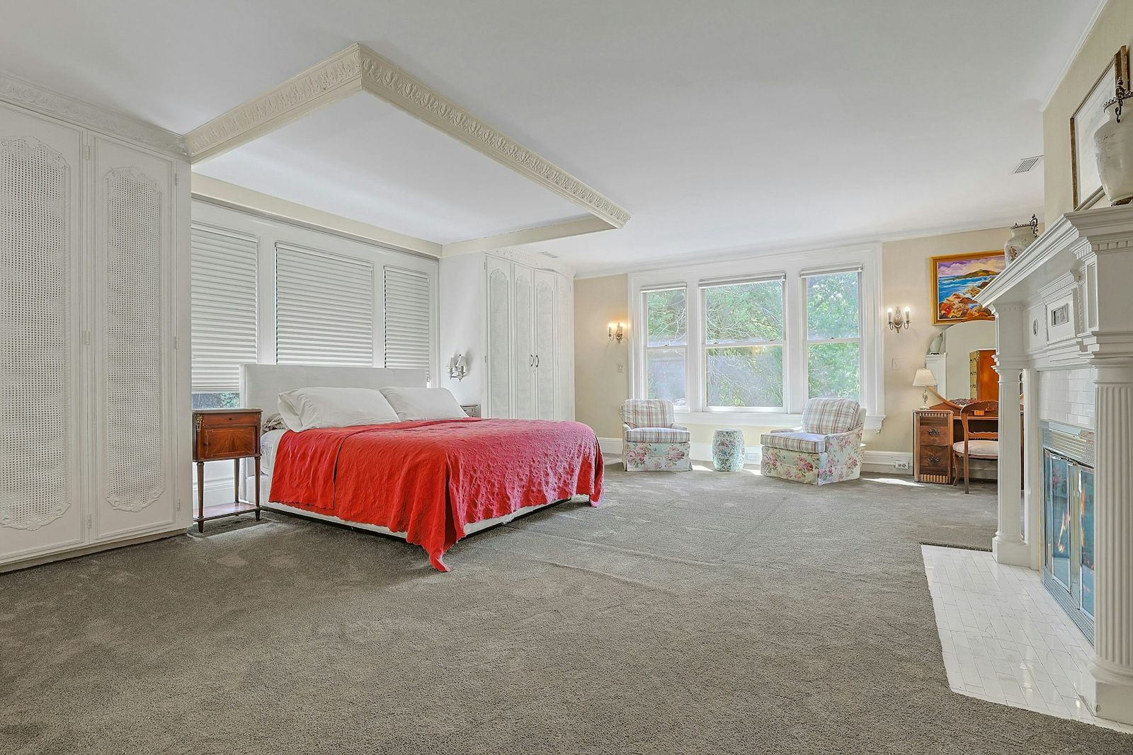 The primary suite opens into an oversized bedroom with a sitting area along a bank of windows overlooking the grounds. 