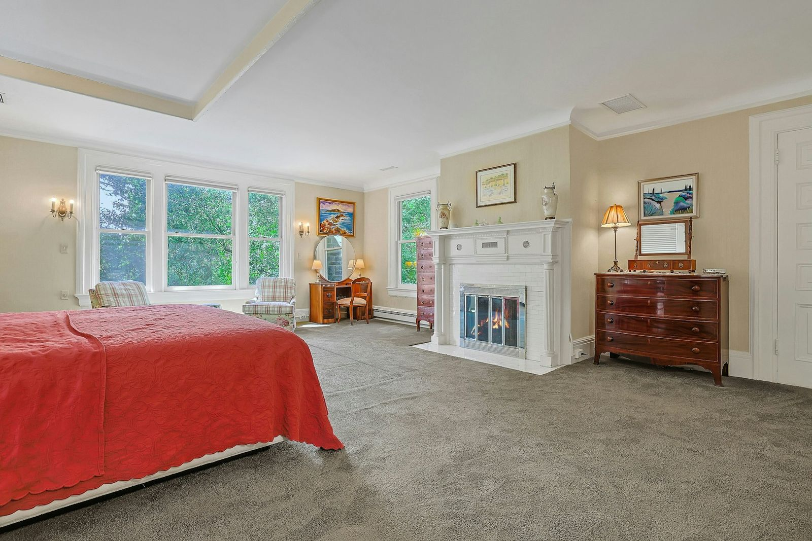 Across from the bed, wardrobes and a vanity frame either side of a white fireplace with classical detailing.