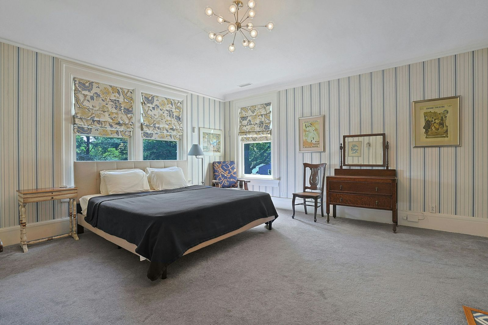 One secondary bedroom is the perfect mix of traditional and modern styling wrapped in vertical-striped wallpaper. 