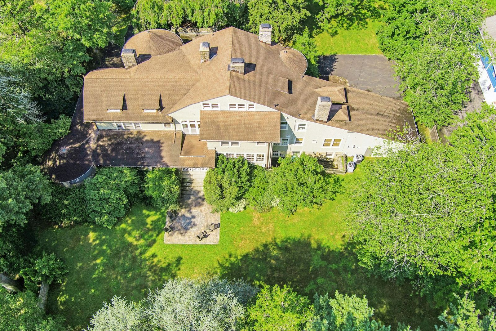 The backyard stretches across the home’s 1.12-acre grounds with a large open lawn framed by towering trees. 