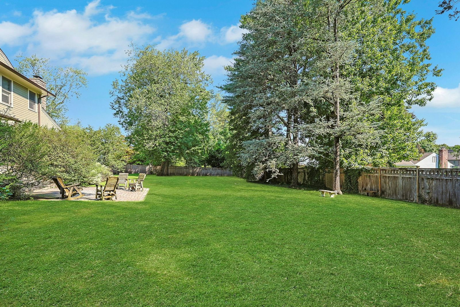 At the bottom of the stairs leading out to the yard, a stone patio provides a place to gather out in the sun, while the rest of the yard opens to the fenced-in grass.
