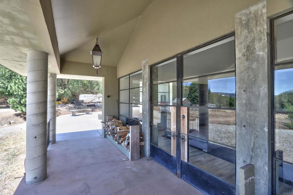 Under the porch, the entry is framed by tall industrial-style glass doors, giving the exterior a more modern edge while allowing a clear view into the interior before stepping inside.