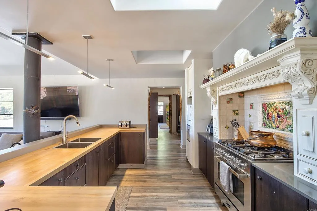 Across from the prep counter, a stainless-steel range is set beneath a carved surround with decorative tilework.