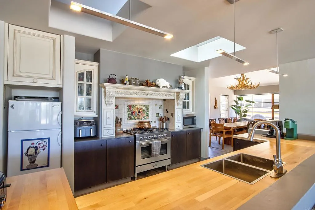 The kitchen is set up as a long U-shaped work area lined in dark lower cabinetry and thick butcher-block counters.