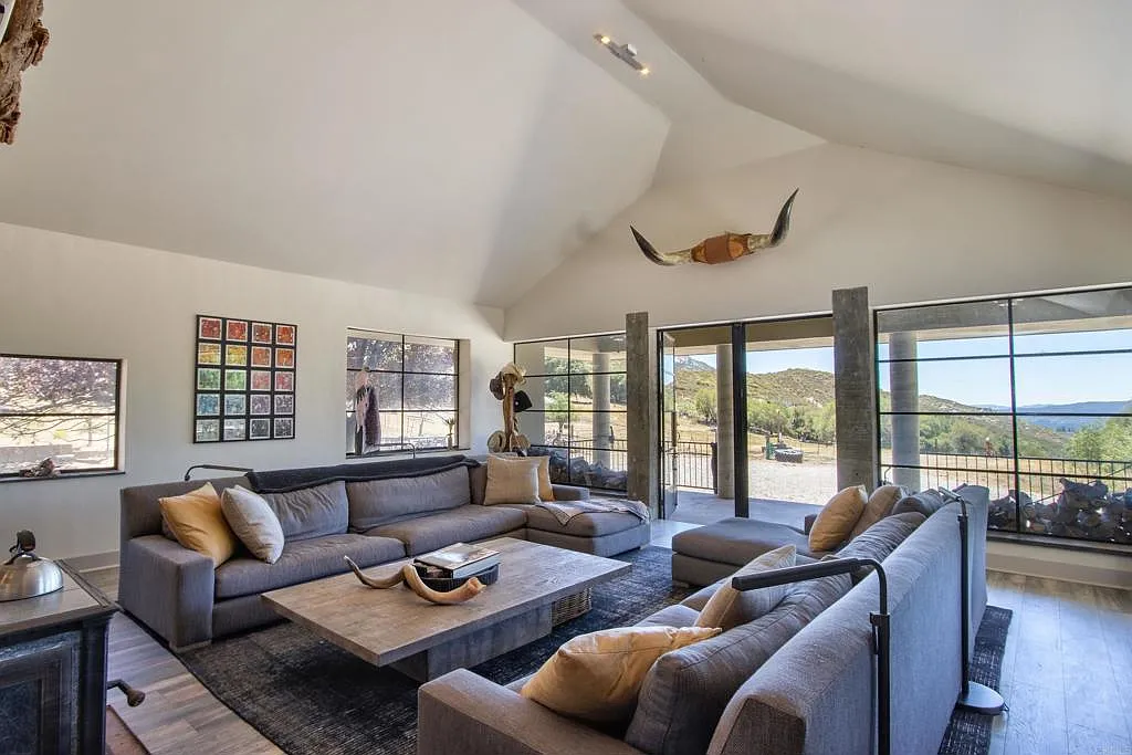 The entry's large black-framed windows and glass doors line the opposite side of the room, pulling in views of the surrounding mountains.