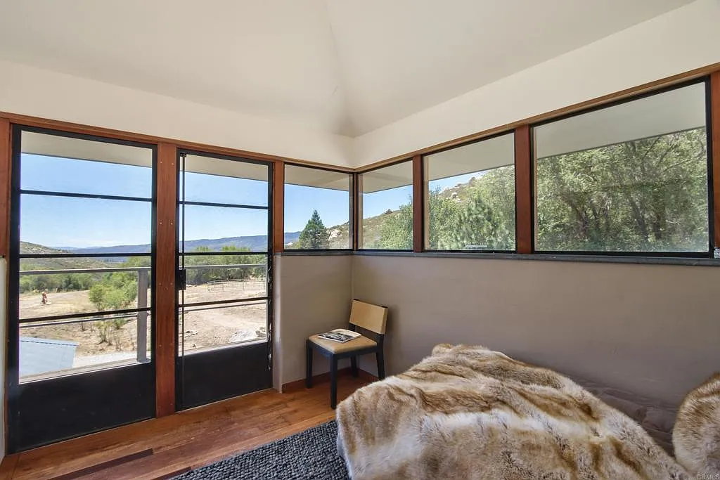 A set of glass doors opens directly onto a private balcony at the front of the house, extending the bedroom outdoors.