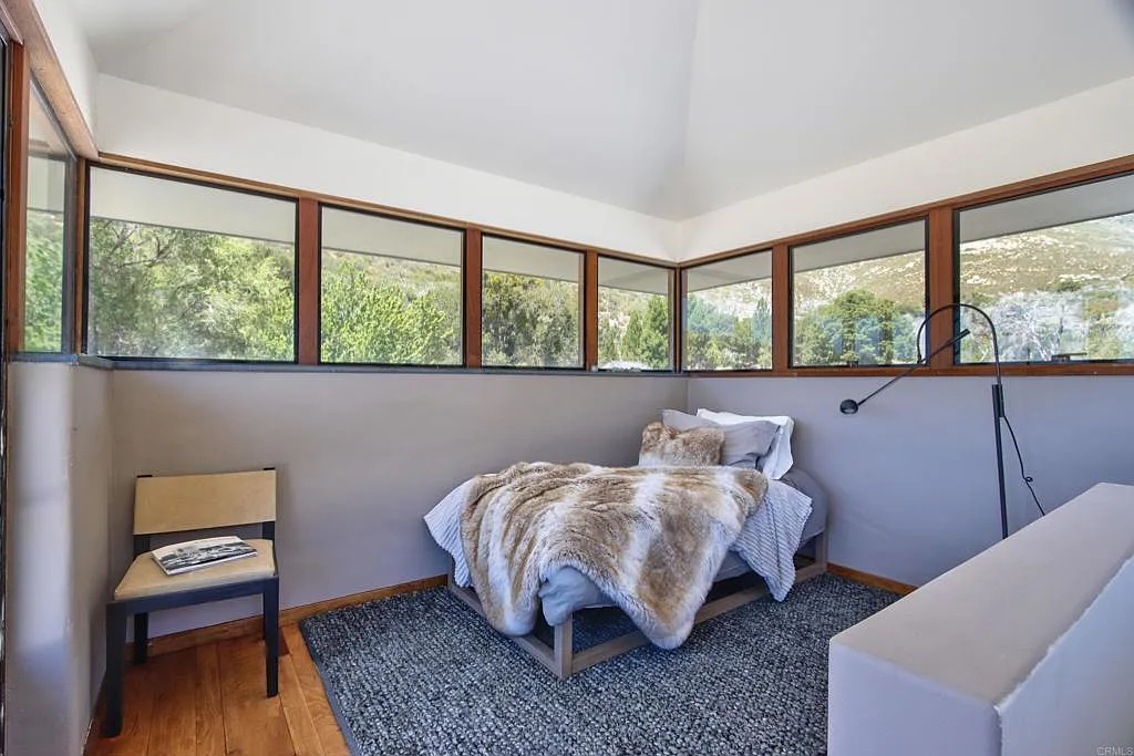 the loft bedroom is wrapped in a band of windows that follows all sides of the room.