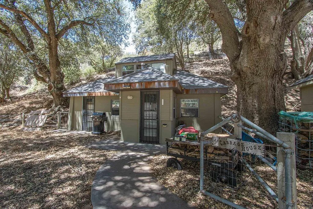 Tucked beneath the trees, the caretaker house sits in a more shaded part of the property with its own walkway and private entrance. 