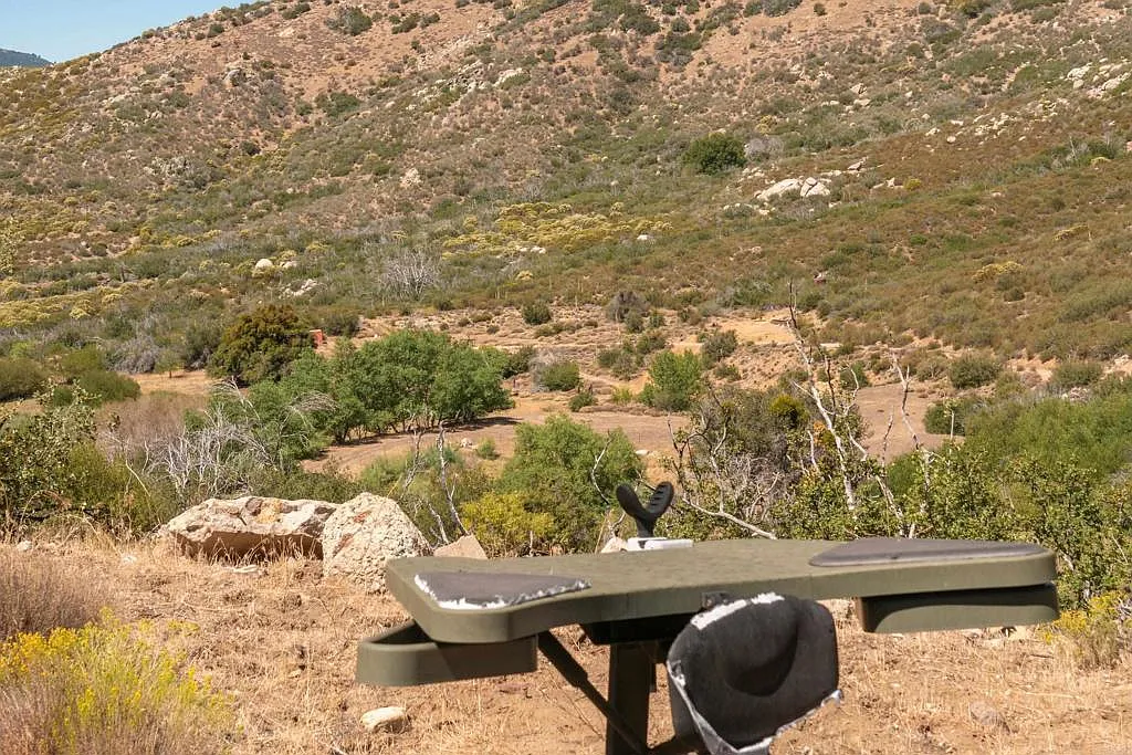 Elsewhere on the property, a private 300-yard shooting range is positioned against the surrounding hills, with a shooting area looking out across the open terrain.