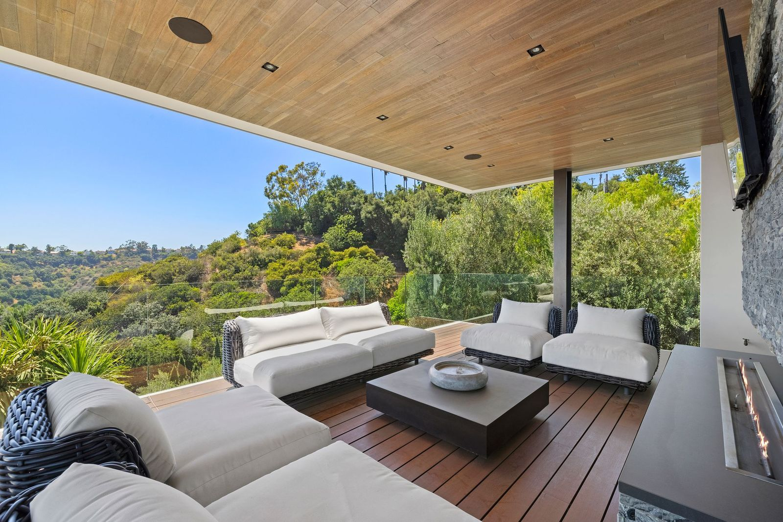 The suite opens onto a private balcony overlooking the surrounding canyon, furnished with a white lounge set facing a TV and fireplace.