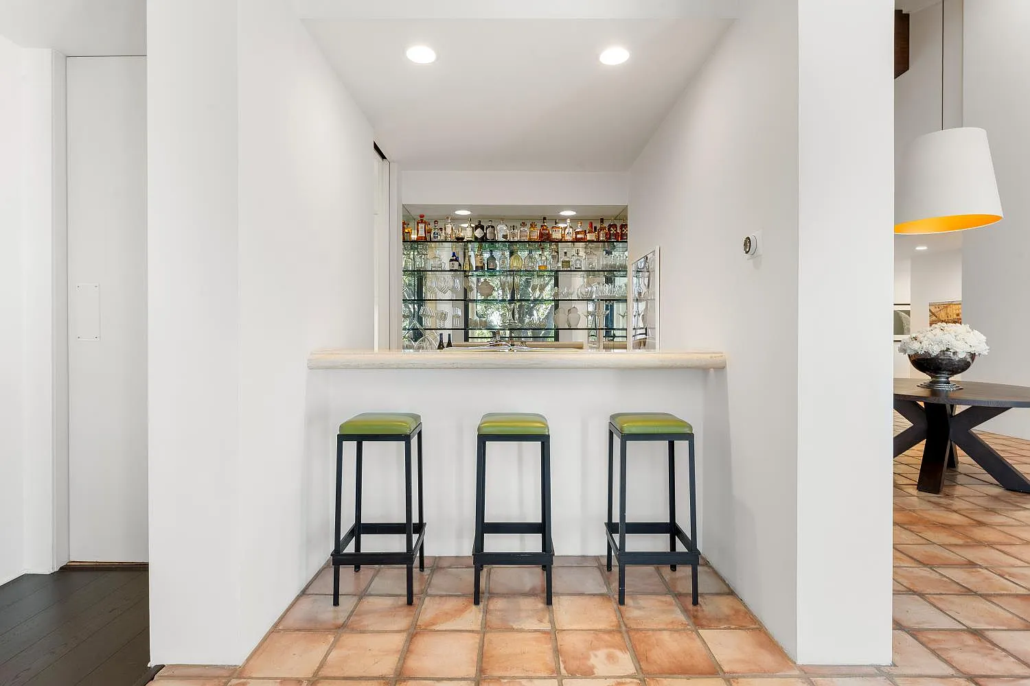 A built-in bar with mirrored shelving and barstool seating.