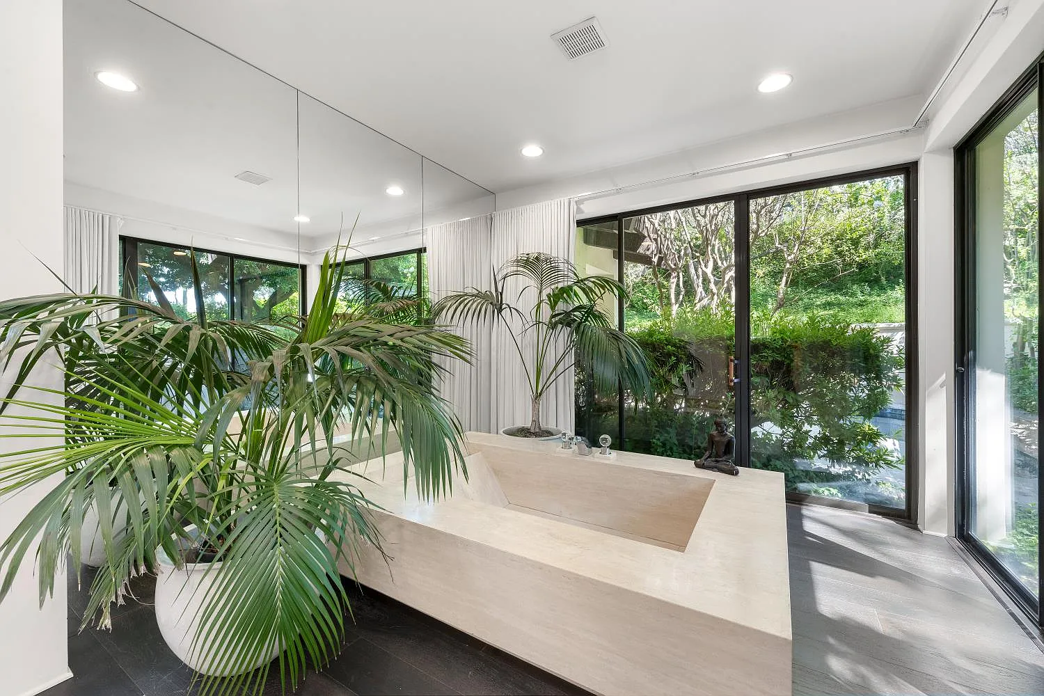 An oversized soaking tub sits in a neutral part of the bathroom, tying the two private spaces together with access to the wellness courtyard.