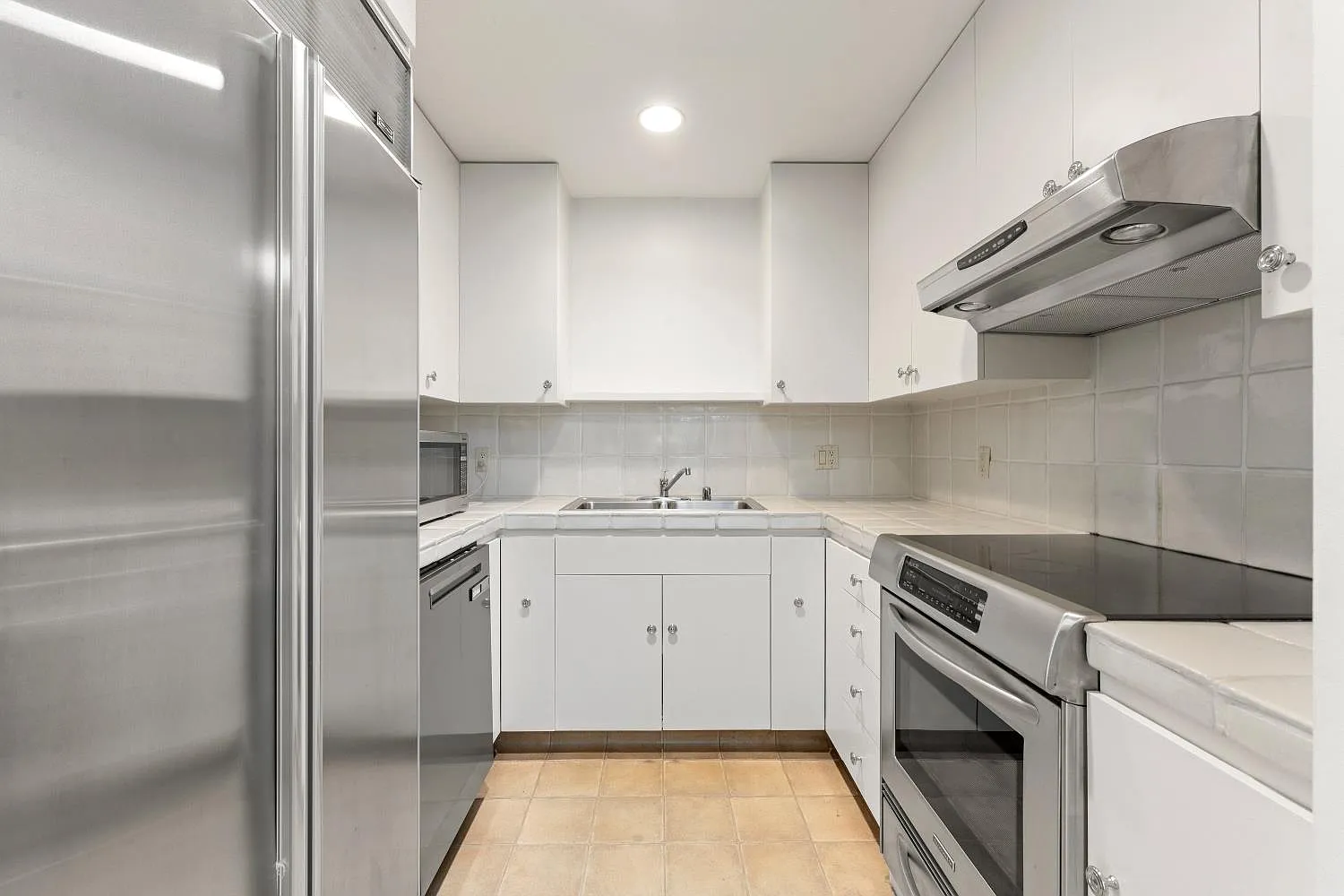 Compact kitchen with white cabinetry and stainless steel appliances.