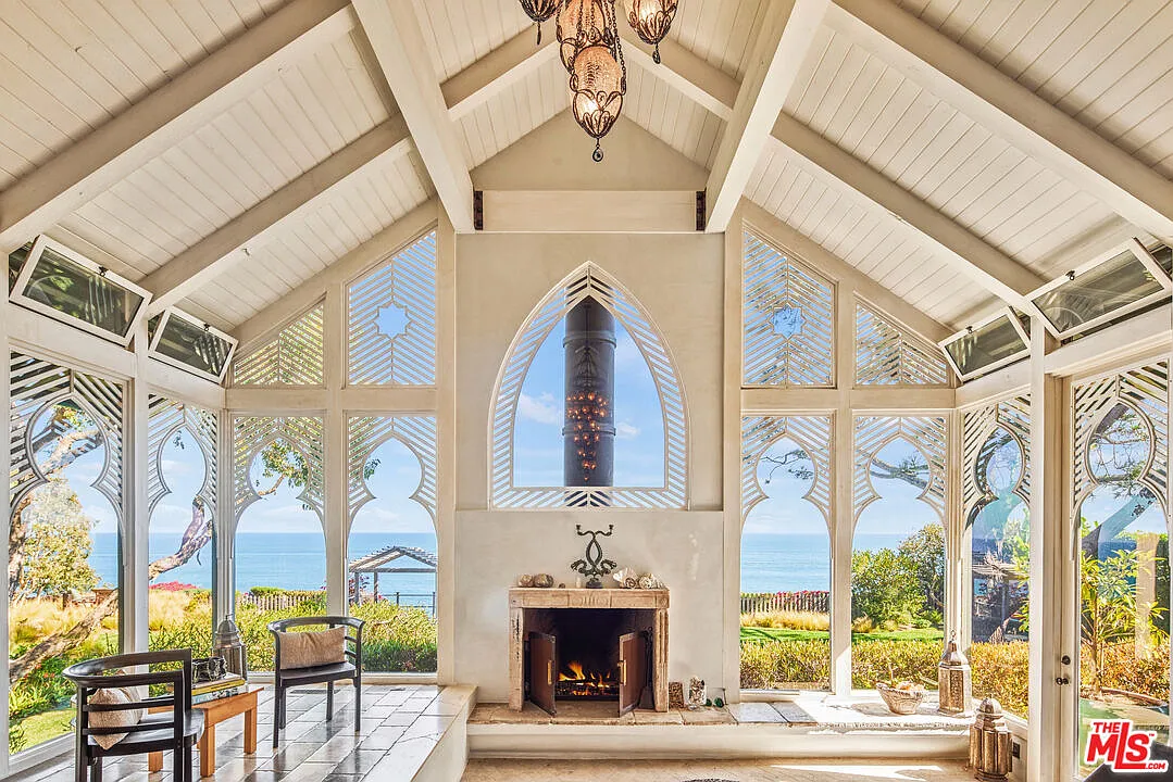 The home opens into a living room beneath soaring beamed ceilings lined in full wall windows.