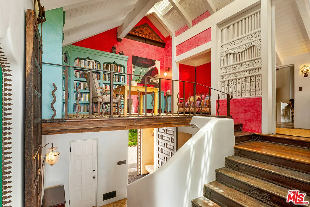 The staircase branches off to an open landing that has been transformed into a colorful library.