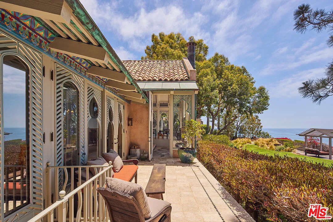 An outdoor deck runs along the ocean-facing side of the house