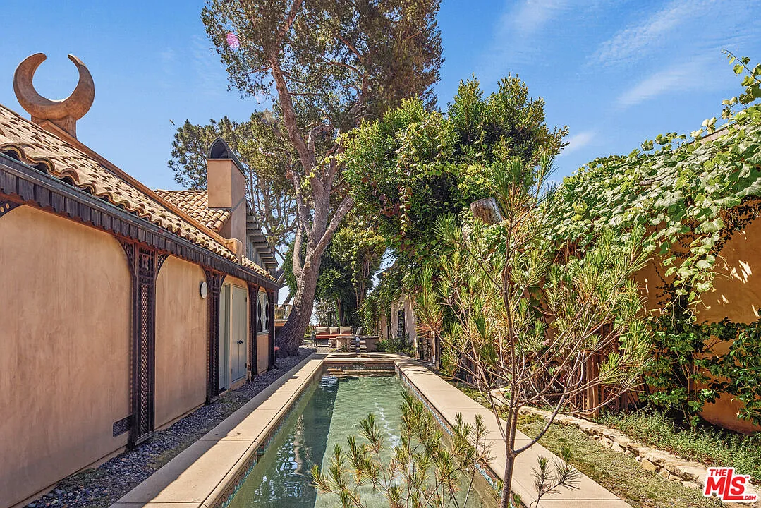 Along the side of the house, a long narrow pool is tucked between the residence and dense landscaping.