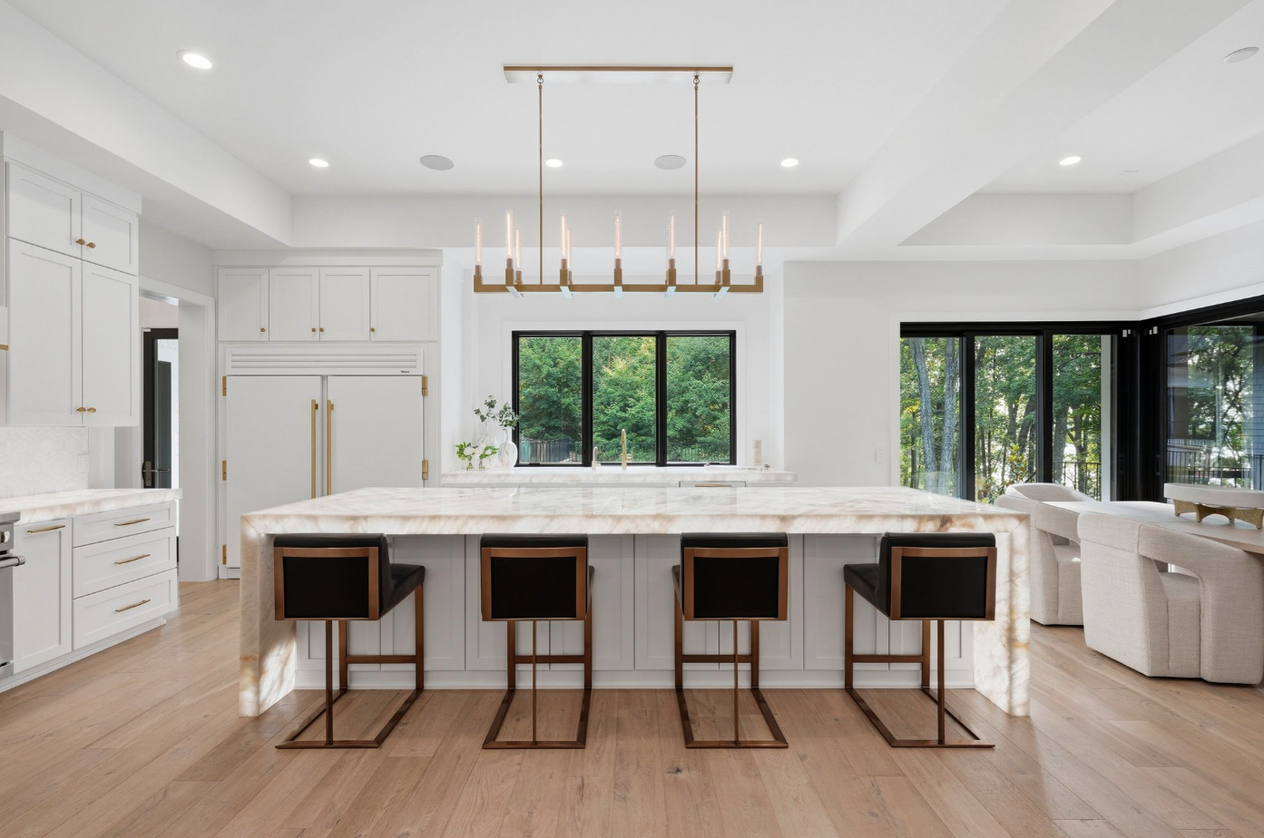 The kitchen is built around a sculptural Crystalita stone island that stretches through the center beneath a linear brass pendant. 