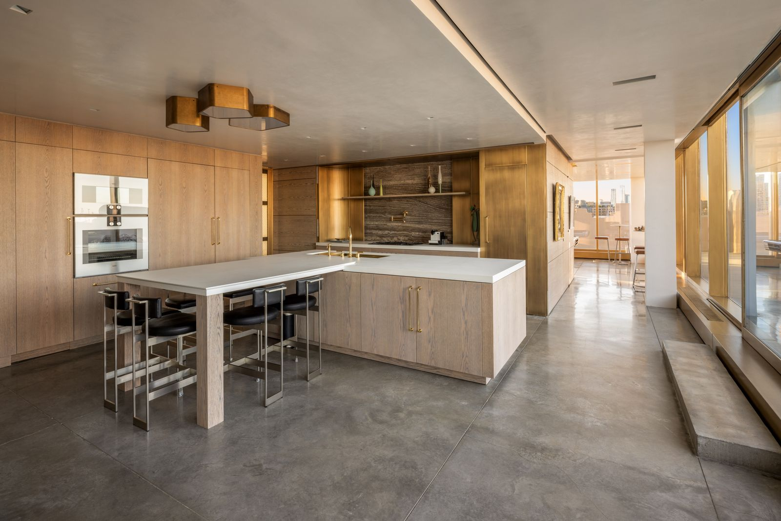 The eat-in kitchen has cerused oak cabinetry, slim brass hardware, and Italian silver travertine across the backsplash. 
