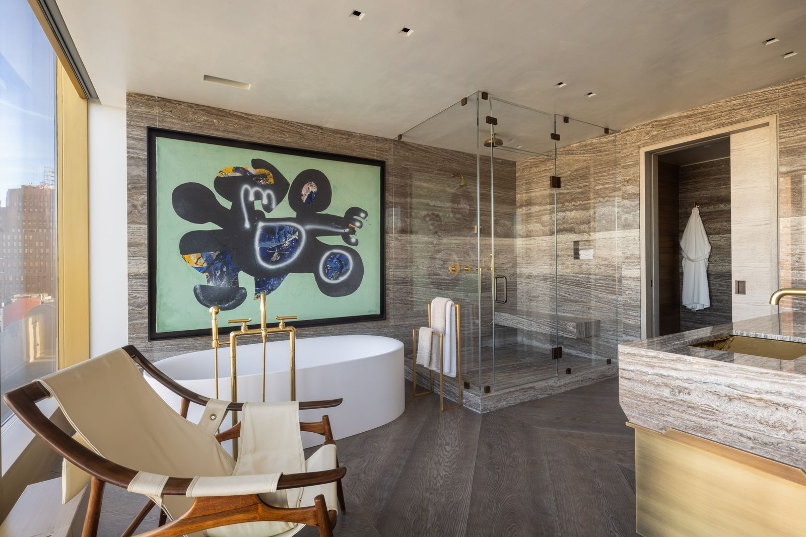 At the far end, a freestanding Boffi soaking tub is placed directly beside the windows, facing toward the river and surrounding towers.