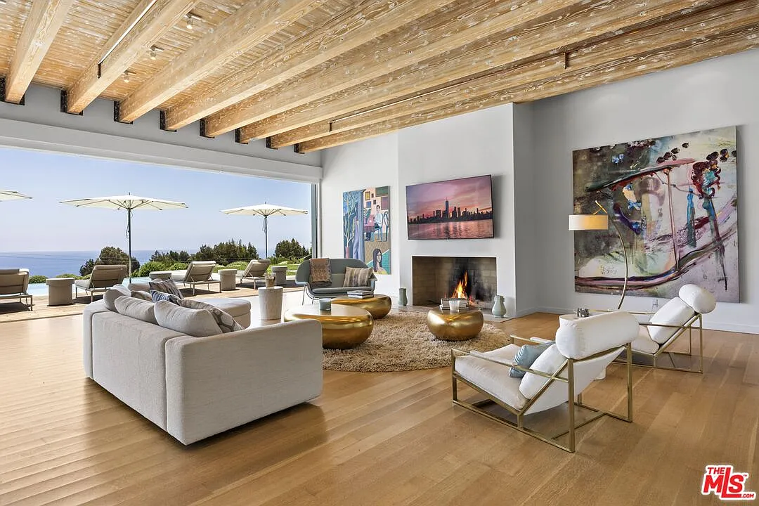 A curved sectional and slim metal-framed lounge chairs form a loose circle around sculptural brass coffee tables, leaving the center open.