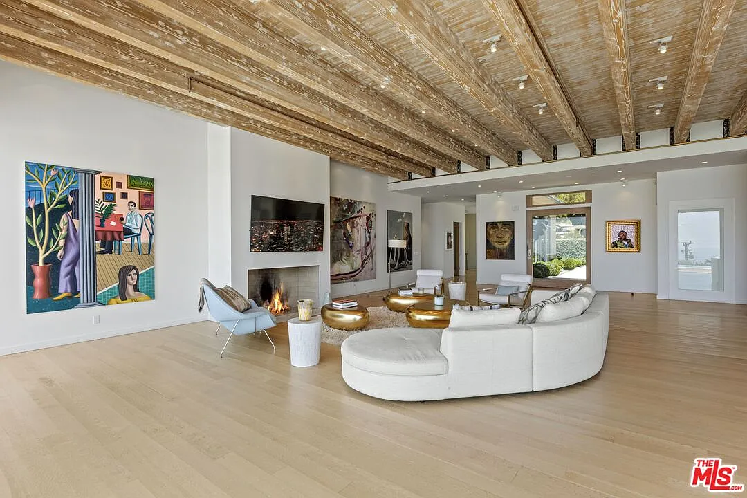 The first living area sits around a fireplace set into a white wall, with large-scale artwork displayed on either side.