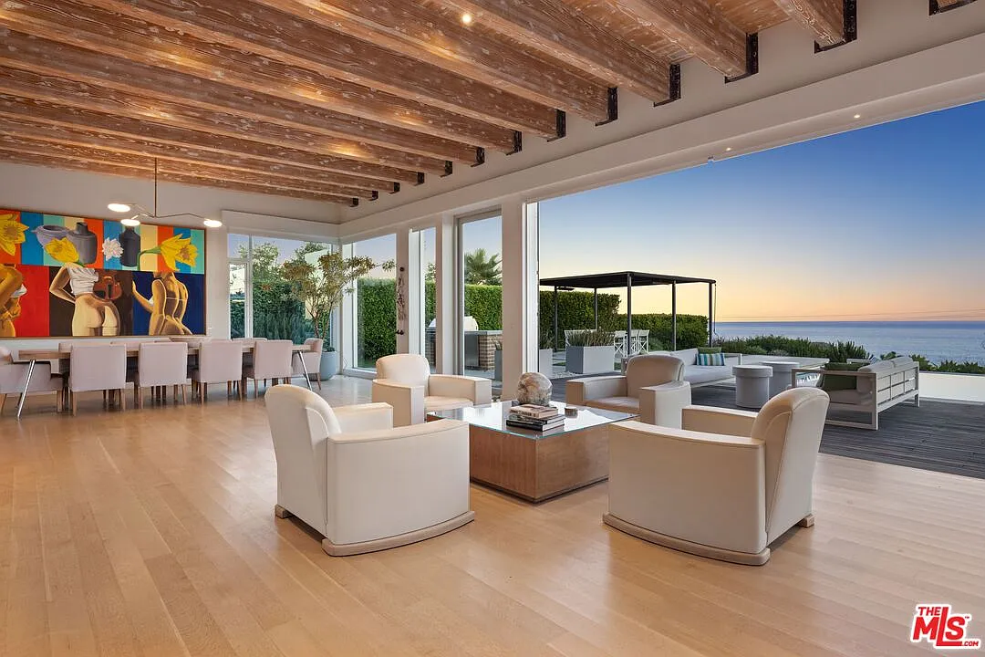 Four white armchairs gather around a low square table, creating a smaller conversation zone between the main living room and dining area.
