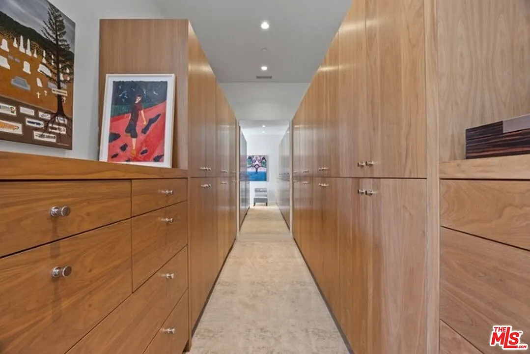 Past the bathroom, the suite continues into a long walk-in closet lined on both sides with full-height wood cabinetry.