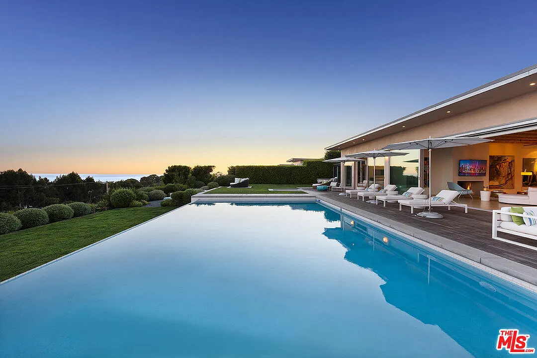 Right in the center of the outdoor space, the pool extends toward the edge of the property, visually meeting the horizon.