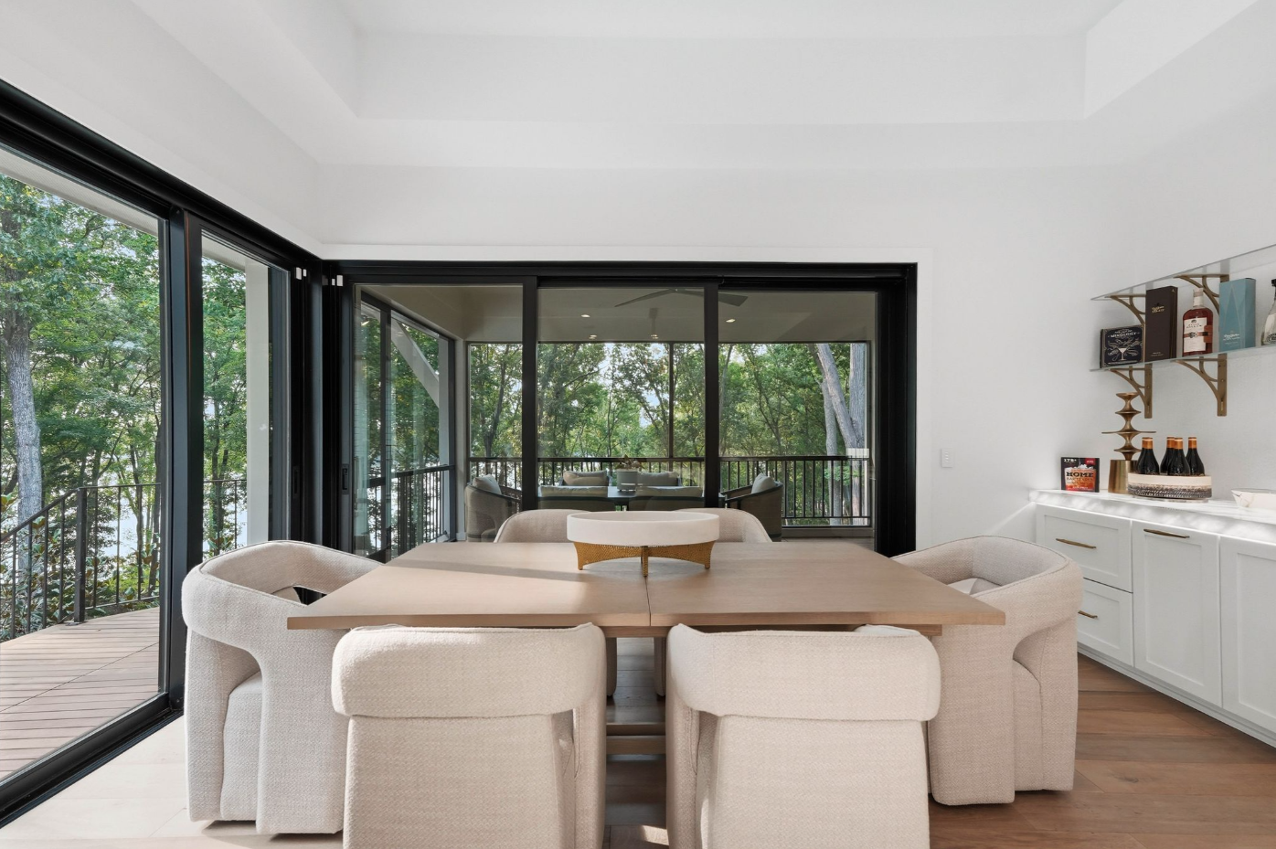 The dining area features a long wood table surrounded by six upholstered chairs. 