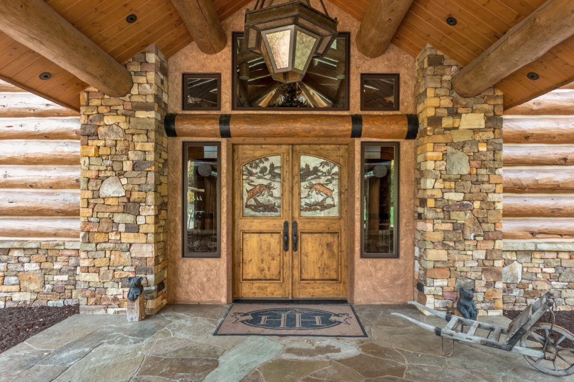 A large lantern hangs overhead as the path leads straight to carved double doors decorated with wildlife scenes.