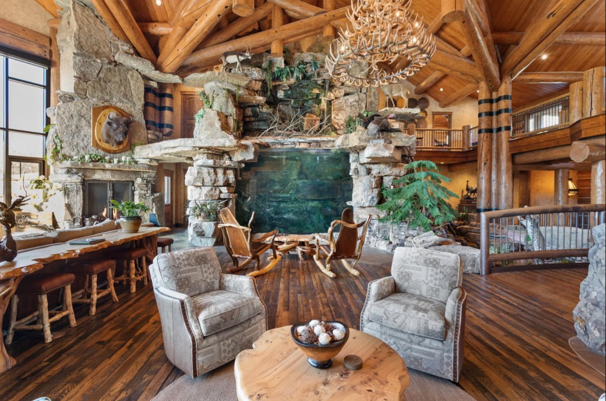 A two-story waterfall and rock structure becomes the focal point, built around an 8,700-gallon freshwater aquarium and layered with natural stone, branches, and wildlife displays.