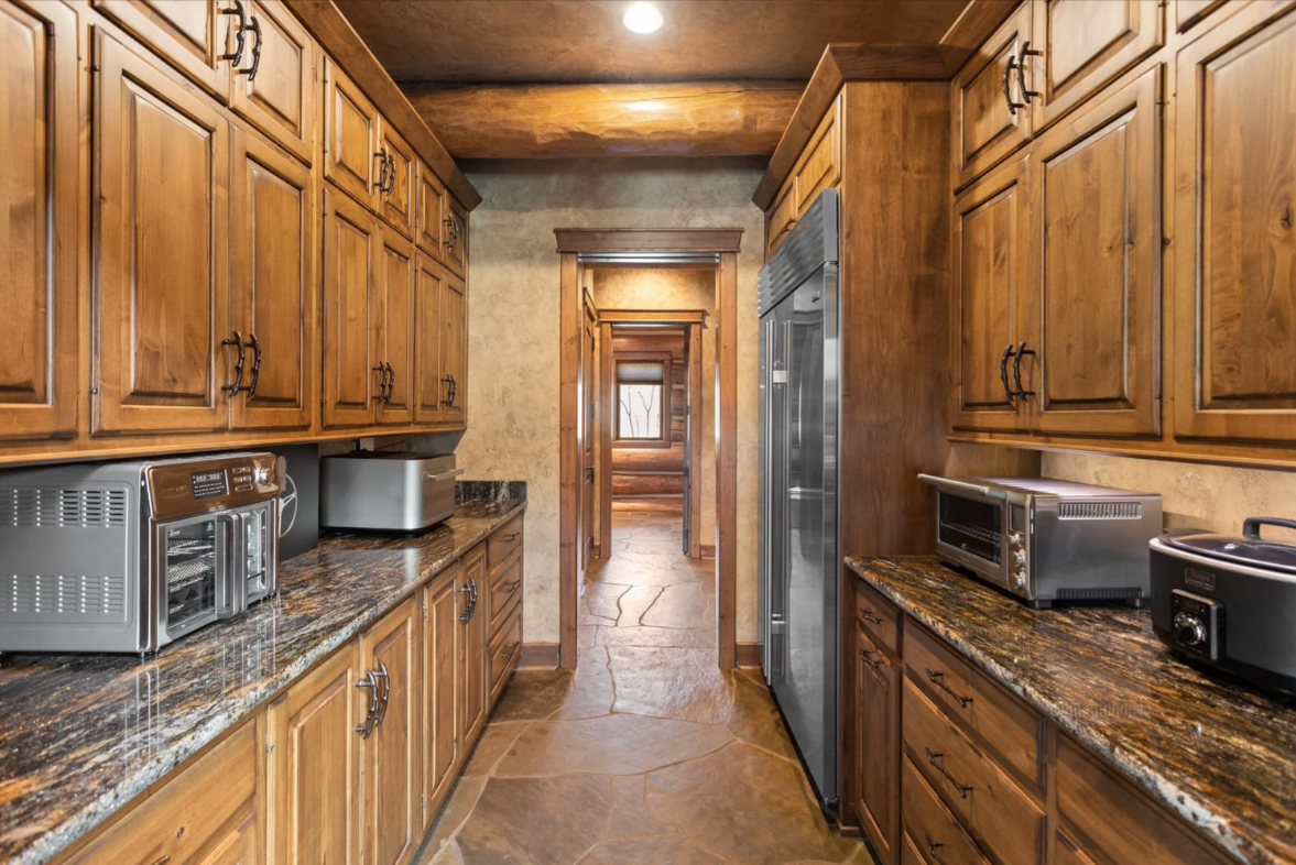 Additional refrigeration, storage, and countertop space line both sides, creating a dedicated prep area tucked away from the main kitchen.