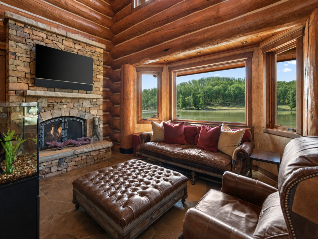 Right next to the kitchen, the den is a smaller, more enclosed sitting area with leather seating gathered around a stone fireplace and mounted TV.