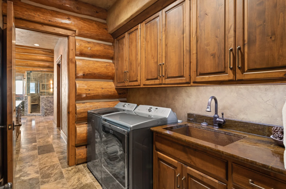 A sink and additional storage sit beside a full-size washer and dryer, creating a private wet bar and laundry space before reaching the bathroom.