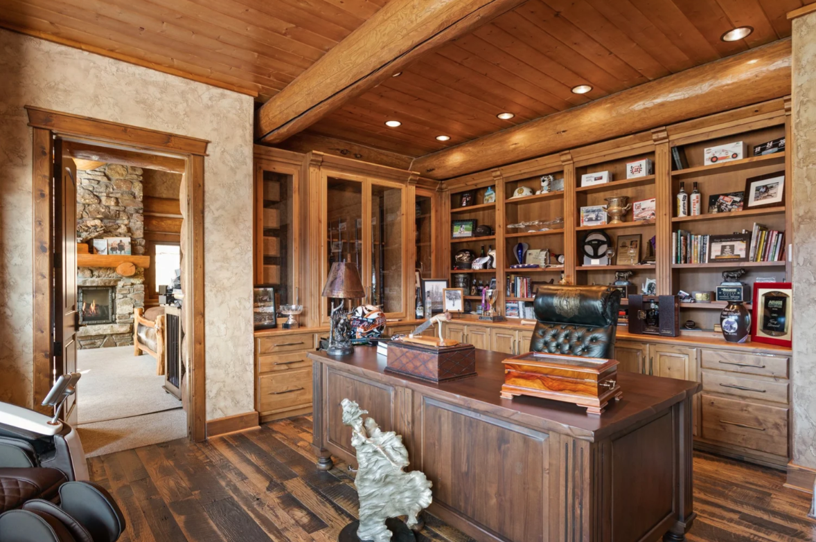 Connected directly to the bedroom, a private office continues the suite with a large wood desk positioned in front of floor-to-ceiling cabinetry and bookshelves.