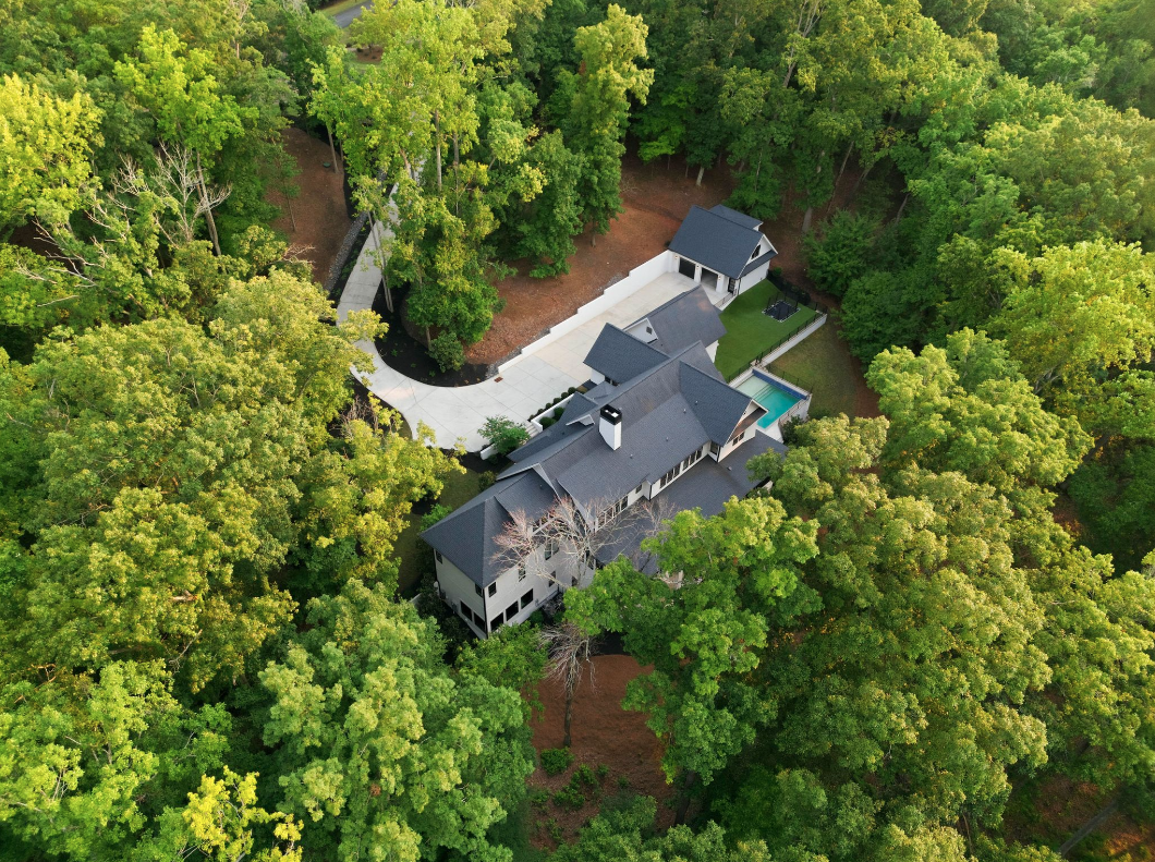 D.J. Moore’s modern Charlotte residence is tucked deep within the trees, with the main structure, pool, and detached garage set along a long private drive.