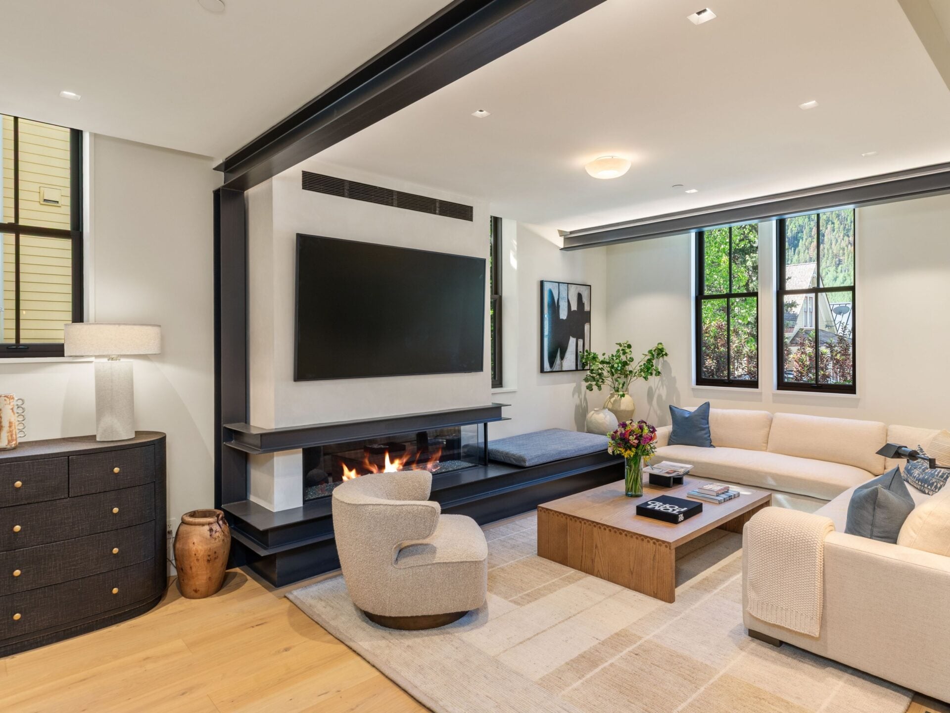 The open layout continues into the living room, where a large couch and rounded lounge chair are placed around a low wood coffee table.