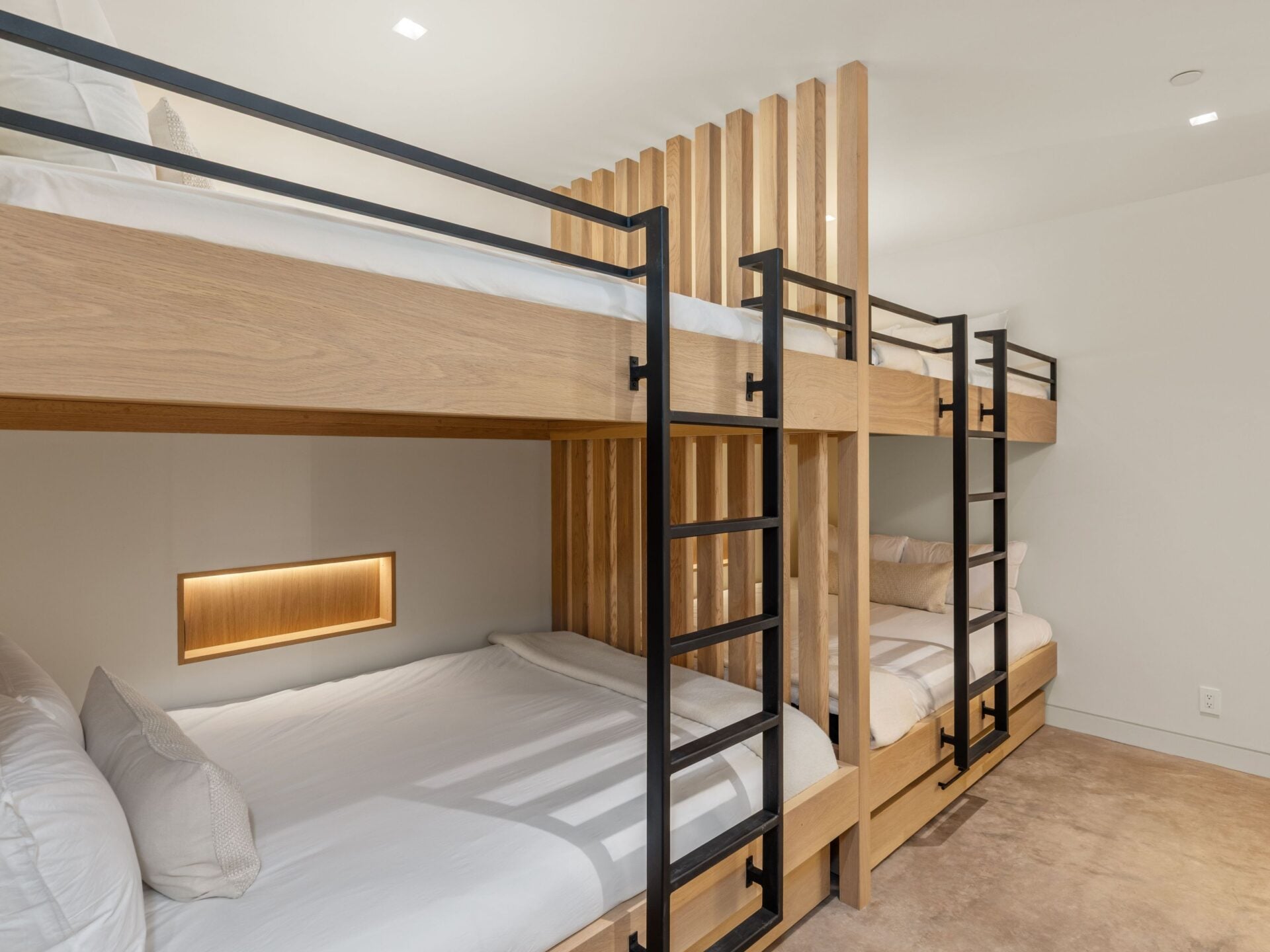 A custom bunk room is designed for larger groups, with two stacked sleeping bays built from matching wood and separated by vertical slatted partitions.