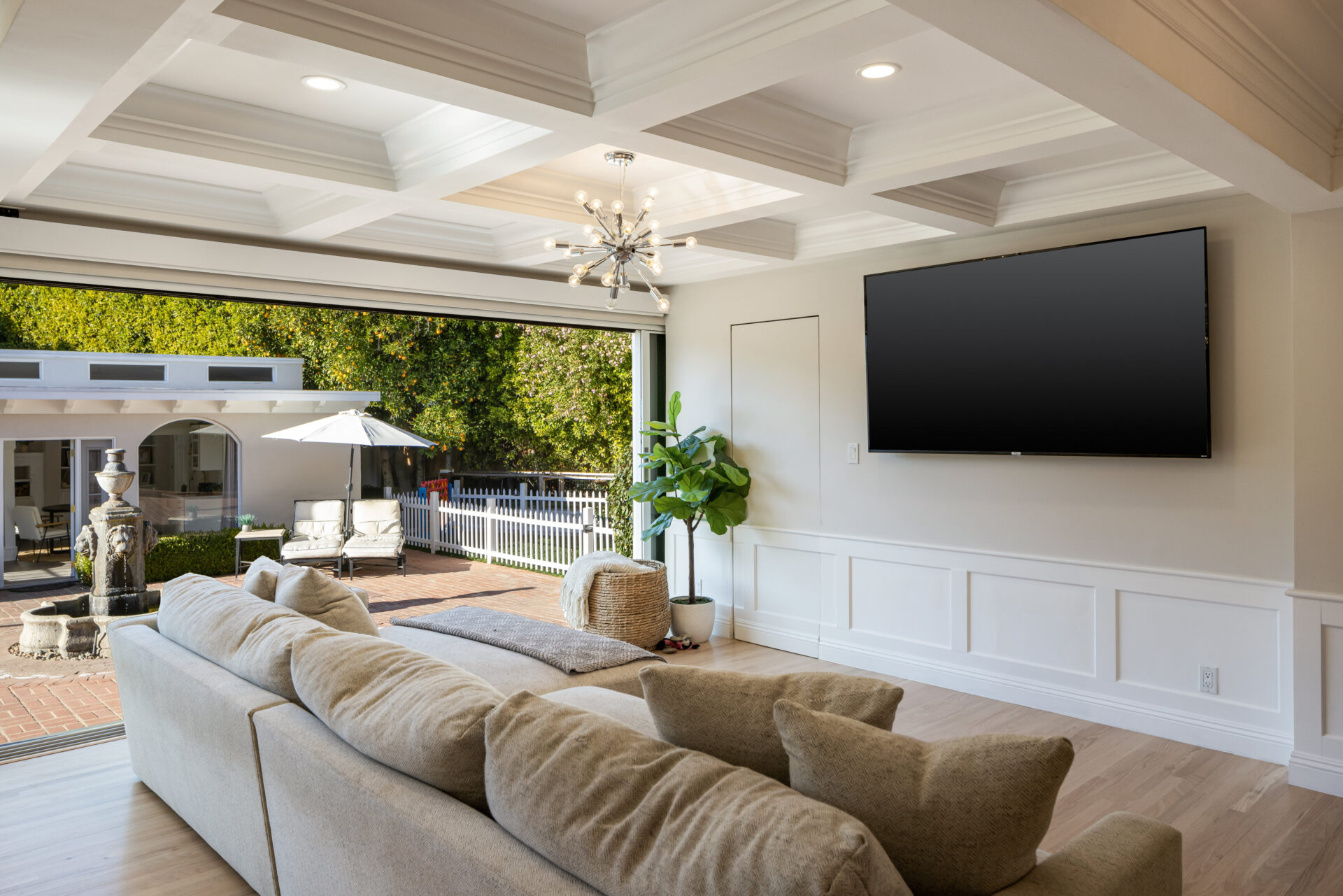 On the other side of the dining area, the family room completes the open living space with a large sectional facing a wall-mounted TV beneath a deep coffered ceiling. 